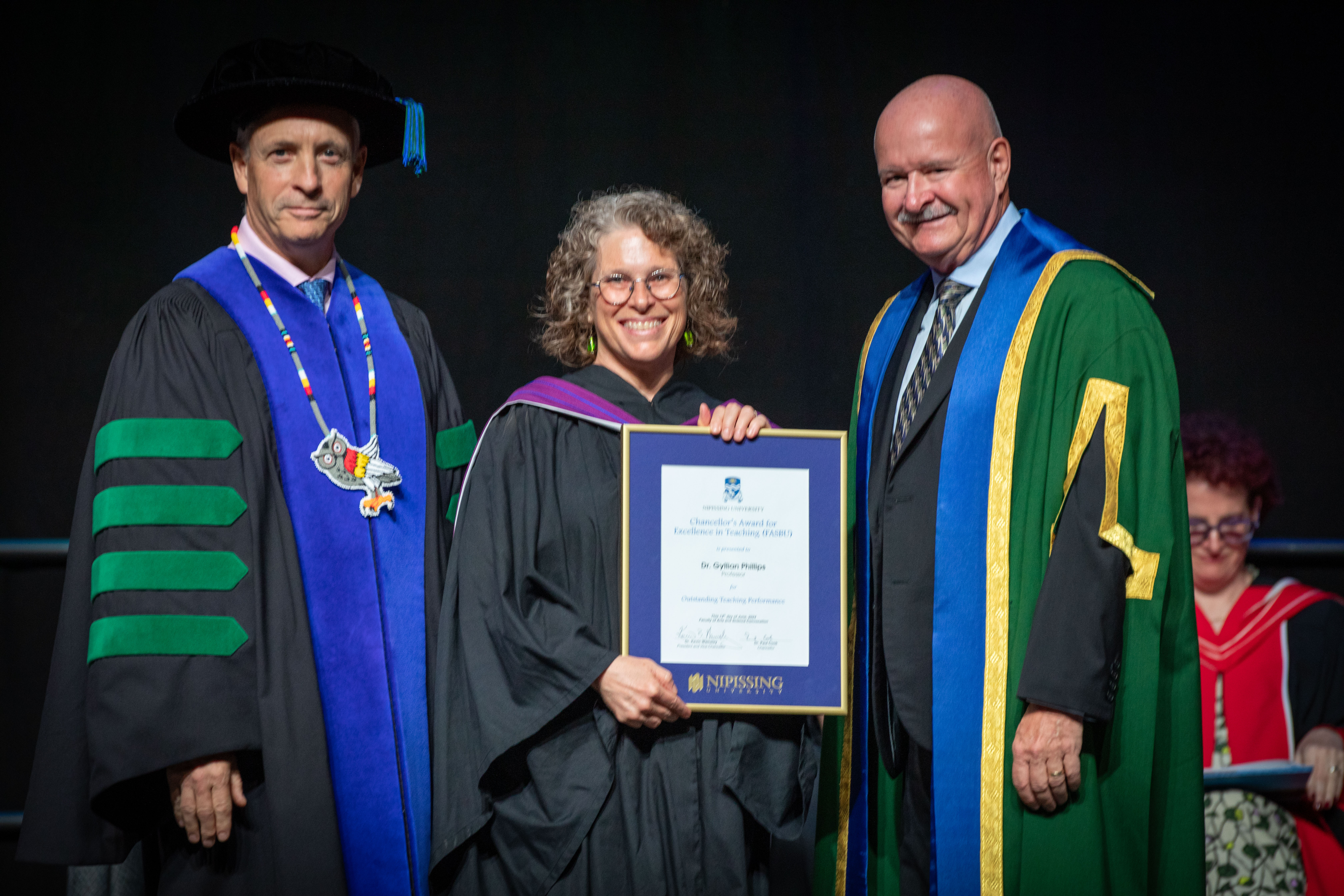 Dr. Gyllian Phillips receiving her award on stage with Dr. Wamsley and Dr. Cook