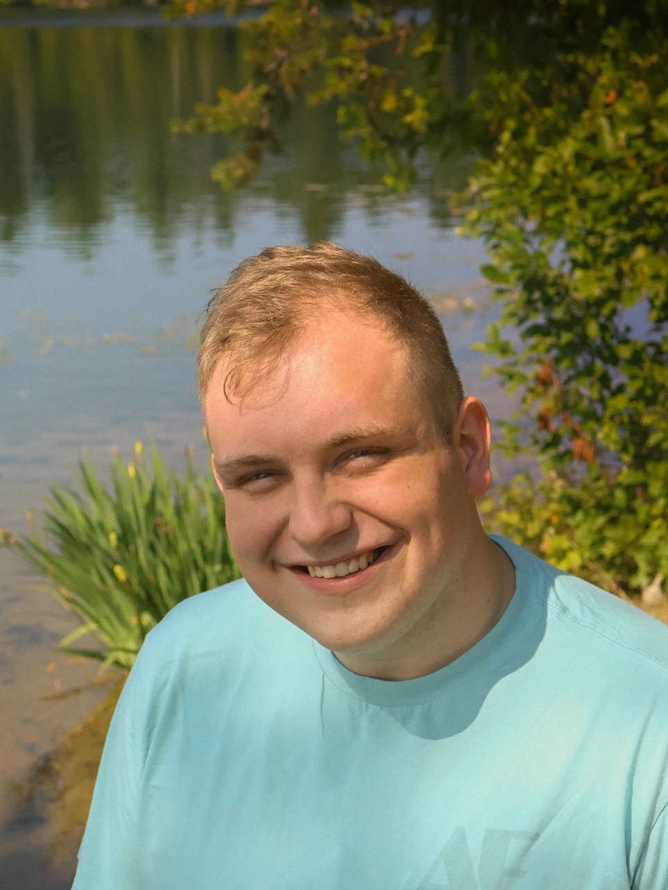 A man in light blue t-shirt against a water background