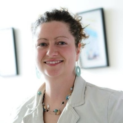 A woman in white top against a light interior background