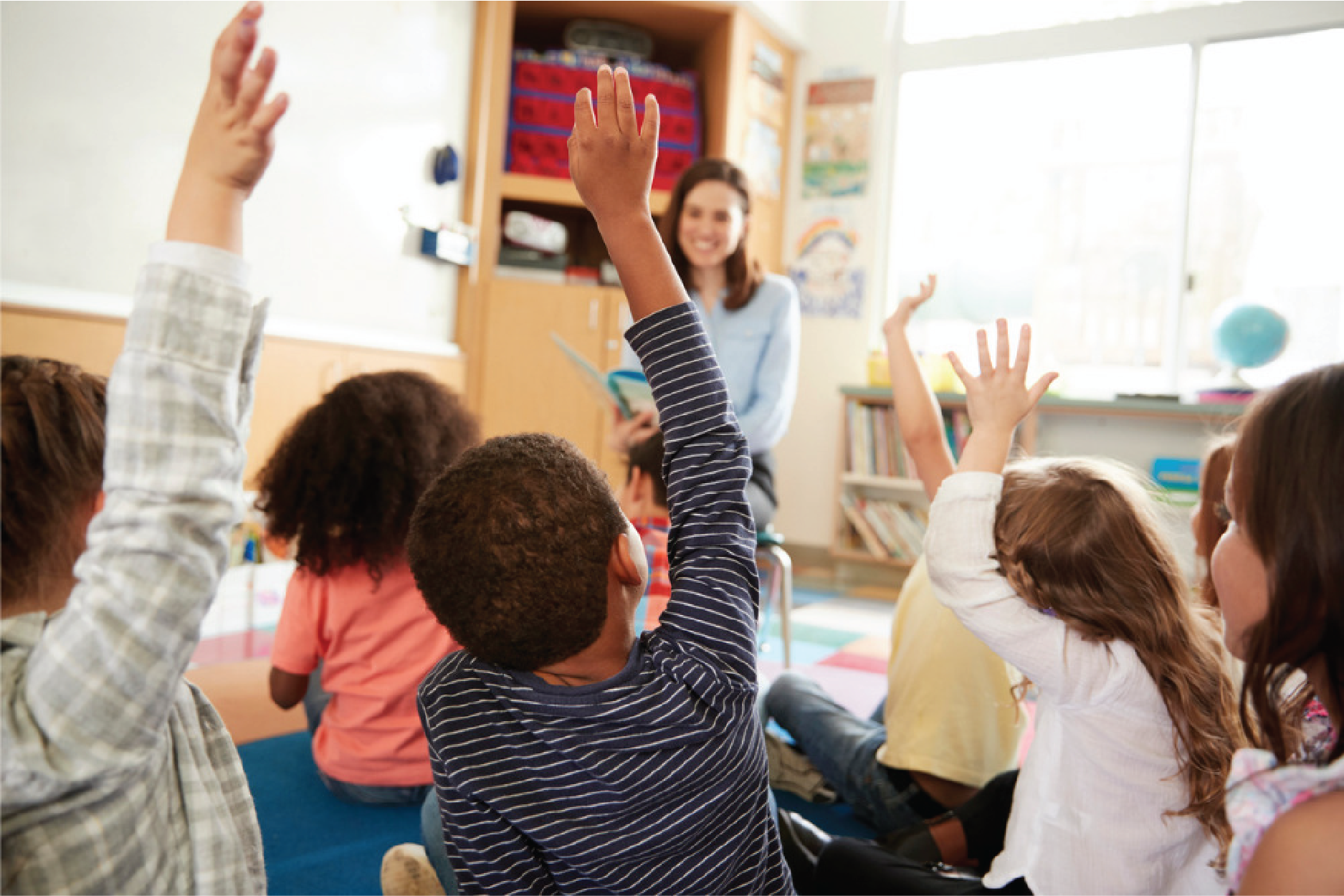 a group of students raising their hands in front of a teacher