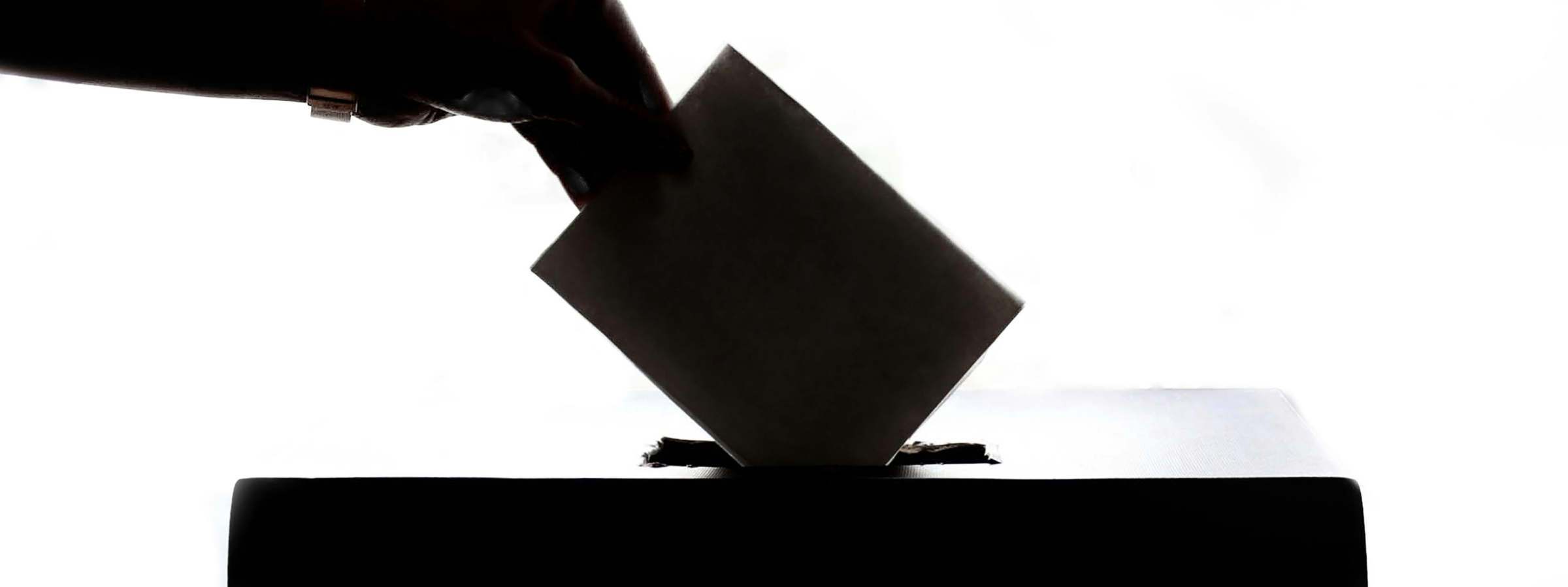 Silhouette of a hand placing a ballot in a box