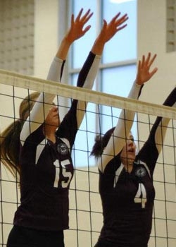 Photo of volleyball players blocking at the net