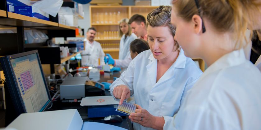 students and instructors examine lab samples