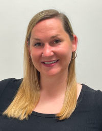 A woman with shoulder length blonde hair in a black top against a white background
