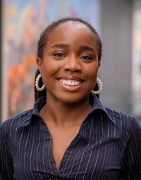 A woman in navy striped shirt in front of a blurred background