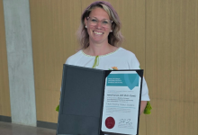 Anna Pearson stands smiling whilst holding her Minister's Award of Excellence