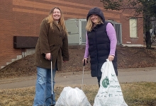 Two Nipissing staff members in front of the building with trash bags and grabbers