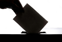 Silhouette of a hand placing a ballot in a box