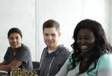Four students seated together smiling at each other.