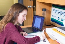 Student studying at desk with laptop