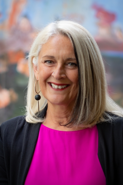 A woman in pink and black top in front of a colorful background
