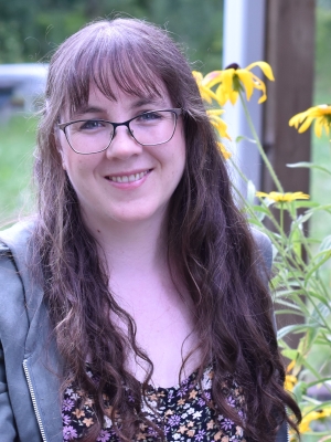 Erin Alladin poses for a portrait with a nature background